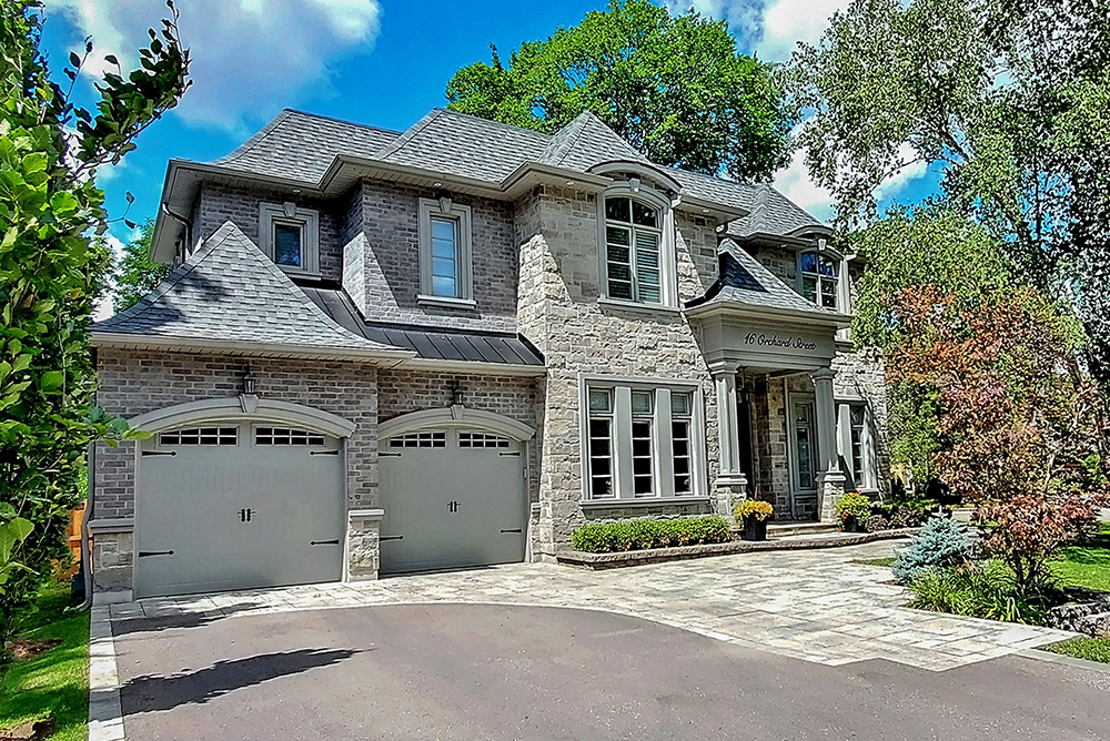 family home features a stone and brick exterior with a unique turreted roofline and a three-car garage